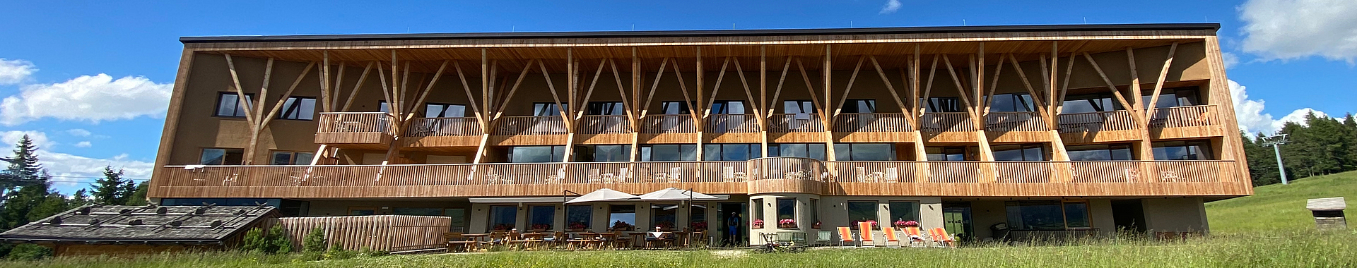 Holzfassade des Gebäudes inmitten einer Wiese in den Alpen.
