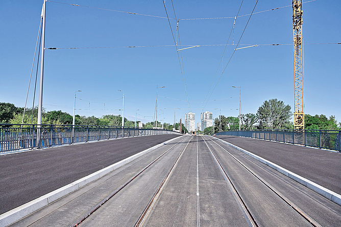 Fertiggestellte, aber noch nicht in Betrieb genommene Brücke mit Gleisen und verschiedenen Spuren daneben.