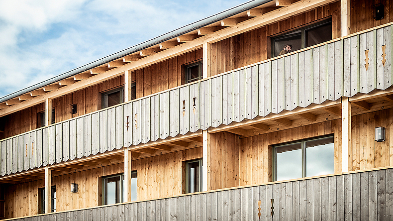 Dreigeschossiges Mehrfamilienhaus mit Holzverkleidung im alpenländischen Stil