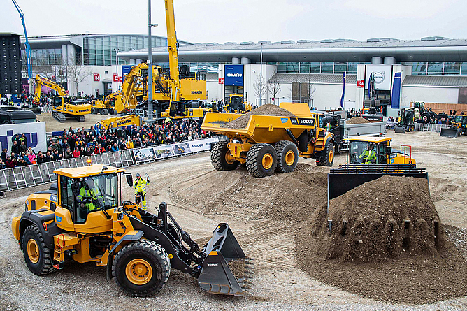 Baumaschinen in Aktion auf dem Freigelände. Baumaschinen im Einsatz auf einem Vorführungsgelände draußen vor den Messenhallen.