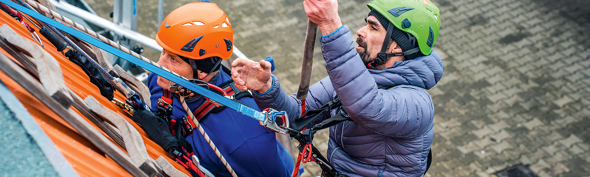 Trainer mit Dachdeckern bei der Unterweisung für Persönliche Schutzausrüstung gegen Absturz. 