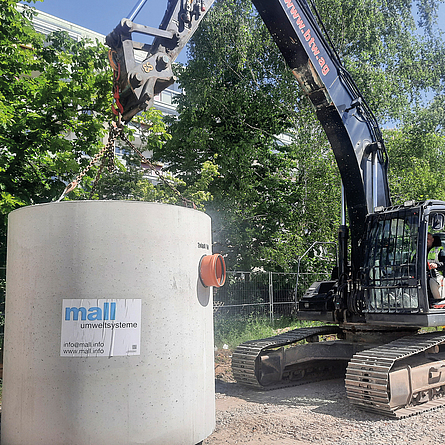 Montage eines Filterschachts aus Stahlbeton-Fertigteilen in monolithischer Rundbauweise mit einem Bagger.