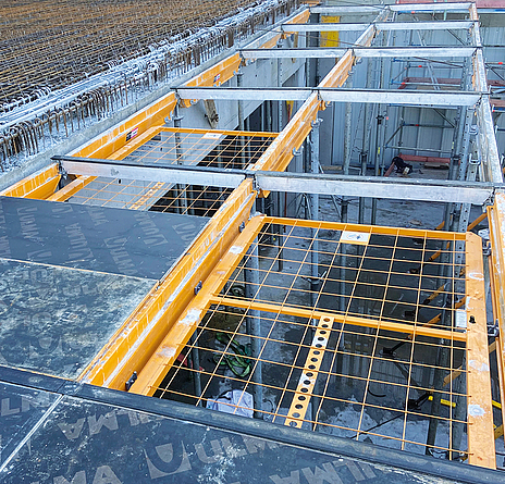 Modulweise werden die Fallschutzgitter weiter verschoben und rasten mittels der integrierten Bremsmechanik automatisch in der nächsten Arbeitsposition ein. Blick von oben auf Deckenmodule, die teilweise abgedeckt sind und teilweise Fallschutzgitter haben.