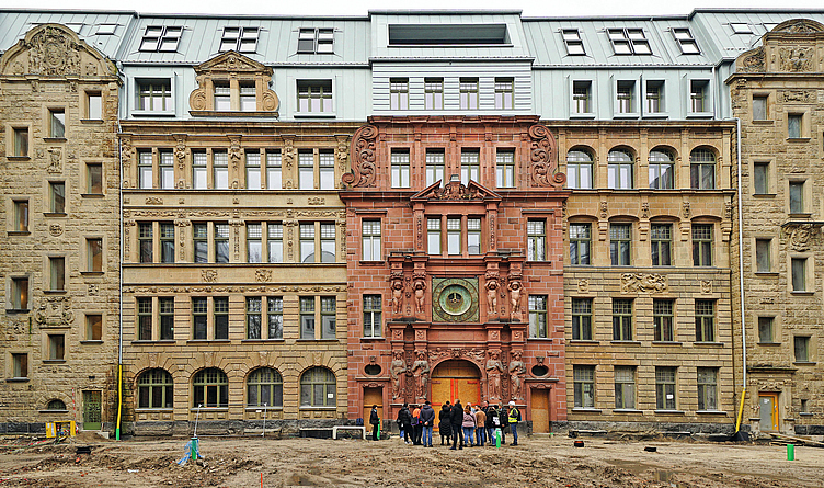 Menschengruppe im Innenhof der Victoriahöfe. Sie stehen vor dem Gründerzeitgebäude. 