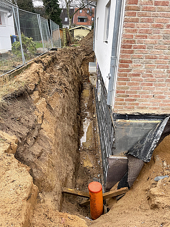 Aufgrund der räumlichen Situation ist bei Kelleraußenwänden oft nicht der normale Böschungswinkel von bis zu 45° möglich. Baugrube rund um ein Haus mit einem sehr steilen Böschungswinkel.