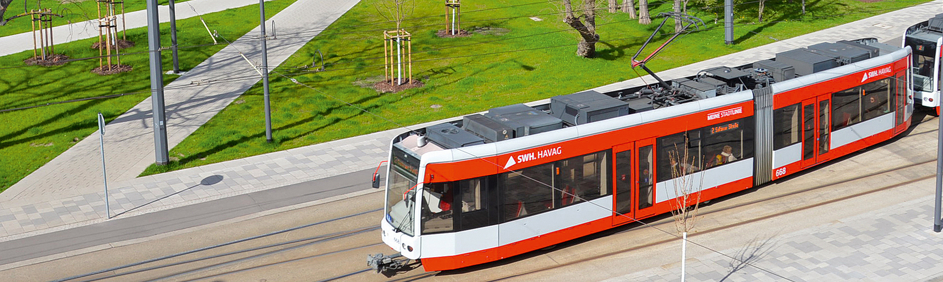 Neuer Umsteigeort am Platz Am Steintor in Halle Eine Straßenbahn hält vor einem begrünten Platz in einem Wohngebiet.
