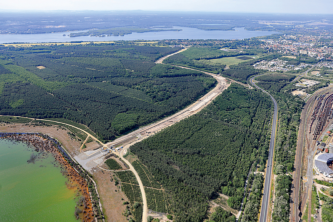 Luftbild des im Bau befindlichen Ableiters zwischen Sedlitzer See und Schwarzer Elster Luftbild auf einen Kanal, der sich von einem See durch einen Wald schlängelt.