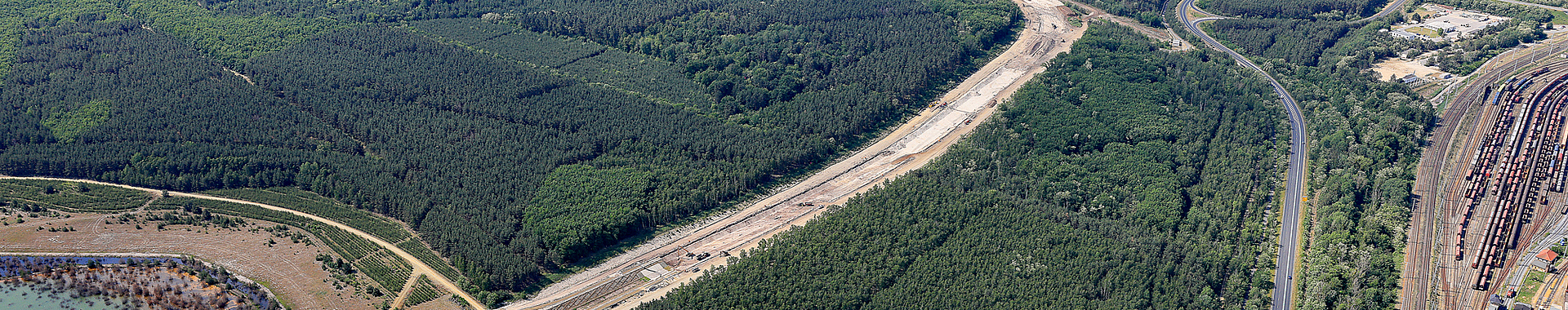 Luftbild auf einen Kanal, der sich von einem See durch einen Wald schlängelt.