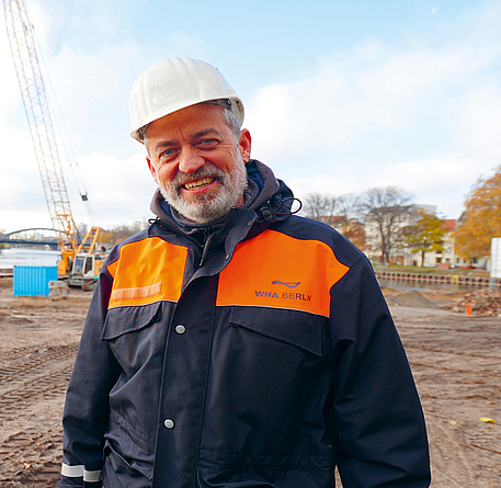 Porträt von Stefan Klähn mit Arbeitsjacke und Helm.