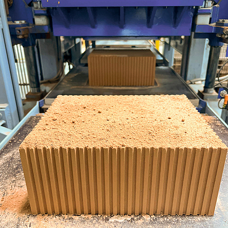 Nahaufnahme eines großen Kaltziegel-Blocks, der aus einer Produktionsanlage kommt.