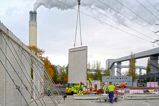 Ein Betonfertigteil für den Campus Reuter wird mithilfe eines Krans montiert. 