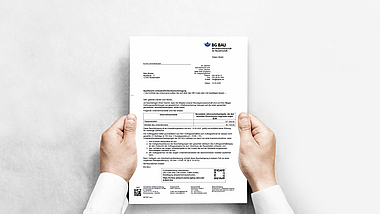 Hände halten das BG BAU Dokument Unbedenklichkeitsbescheinigung.