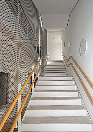 Das Treppenhaus ist oberhalb des Handlaufs auf der zum Rauminneren zeigenden Seite mit Schutznetzen gegen Absturz gesichert.