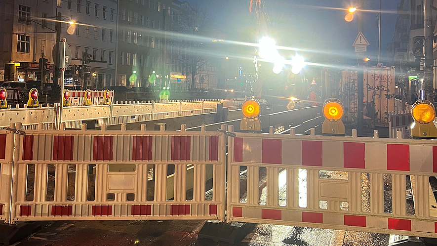 Beleuchtete Straßenbaustelle bei Dunkelheit und Regen.