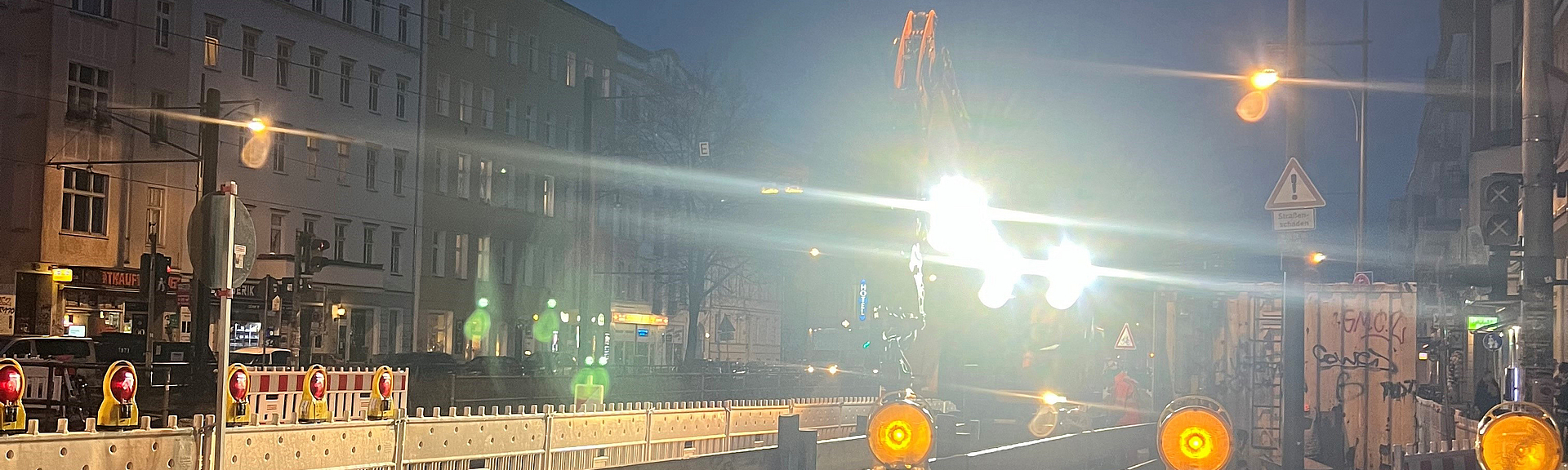 Beleuchtete Straßenbaustelle bei Dunkelheit und Regen.