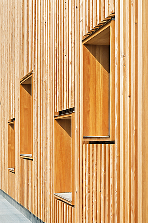 Detailblick auf eine Holzfassade mit vier Fenstern.