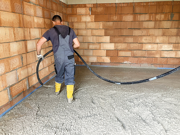 Mit „alcemy“ hergestellter „Low Carbon“-Beton für die Bodenplatte einer Garage wird von einem Beschäftigten per Schlauch eingebracht.