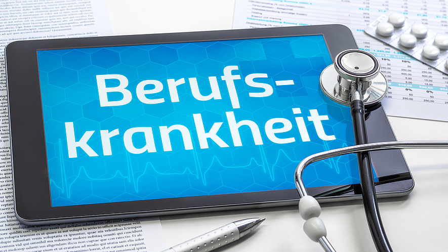 Auf einem Tisch liegt ein Tablet mit der Aufschrift Berufskrankheit. Darüber liegt ein Stethoskop.