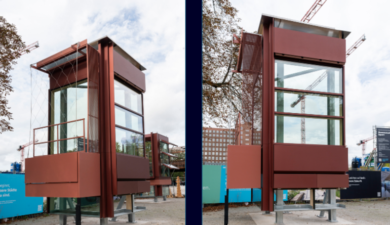 Musterfassade mit rotbraunen Metallverkleidungen und großen Glasflächen auf einem Testgelände.