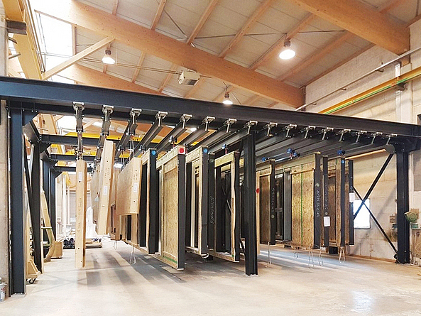 Holzbauteile hängen in einer Halle.