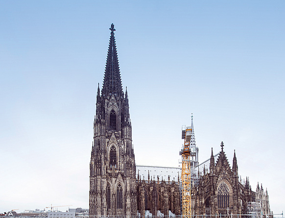 Hotelneubau hinter der unter Denkmalschutz stehenden Fassade des alten Kölner Dom- Hotels. Die Entkernung und der Neubau des Gebäudeinneren erwiesen sich als technisch und wirtschaftlich günstigste Lösung. Gelber Kran vor dem Kölner Dom.