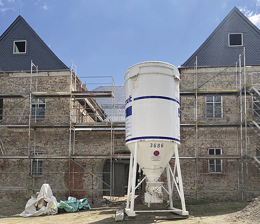 Eingerüstetes Schlossgebäude zu Beginn der Sanierungsarbeiten. Vor dem Bauwerk steht ein Mörtelsilo.