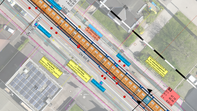 Luftbild mit einem technischen Lageplan einer Straße überlegt. Eingezeichnet sind Leitungen, Schächte und weitere Planungselemente entlang des Straßenverlaufs.