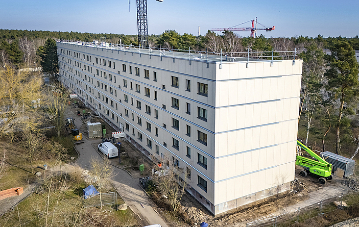 Sanierter Plattenbauriegel mit neuen Fassadenelementen und Absturzsicherung auf dem Dach.