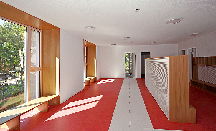 Blick in den Eingangsbereich der neuen Kita: An den Wänden, Fenstervorsprüngen und in der Garderobe schafft der Baustoff Holz eine warme Atmosphäre.
