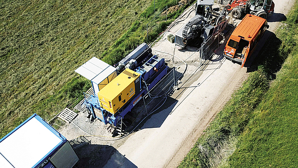 Mehrere Baumaschinen für das Spülbohrverfahren stehen auf einem Weg zwischen zwei grünen Feldern.