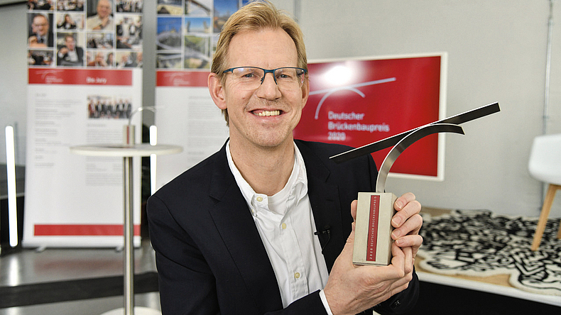 Ein Mann hält eine Auszeichnung in seinen Händen.