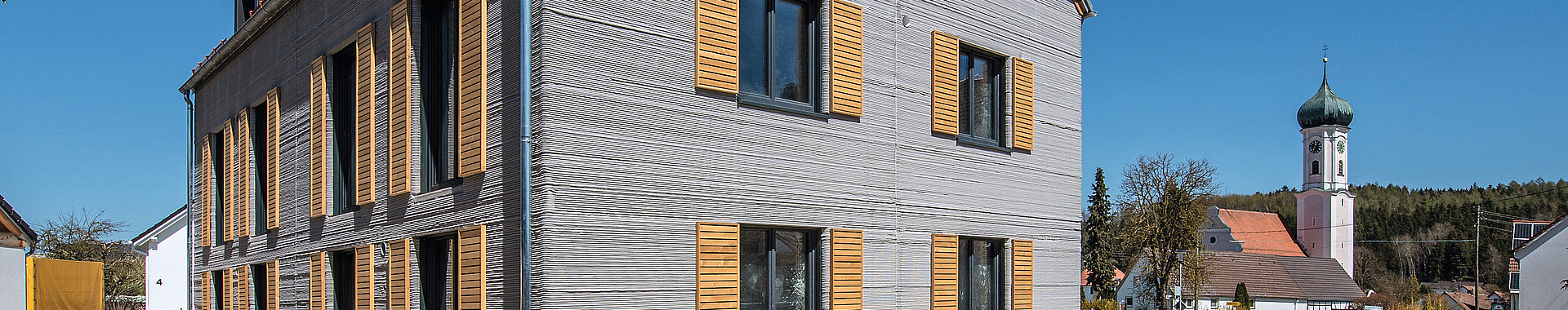 Blick auf das schon fertiggestellte Haus im Baustellenumfeld  