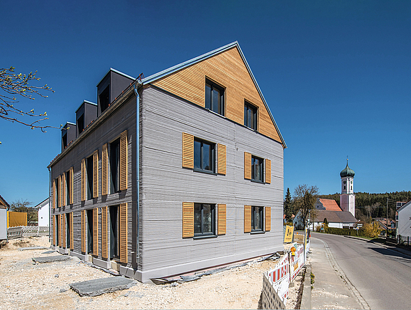 Blick auf das schon fertiggestellte Haus im Baustellenumfeld 