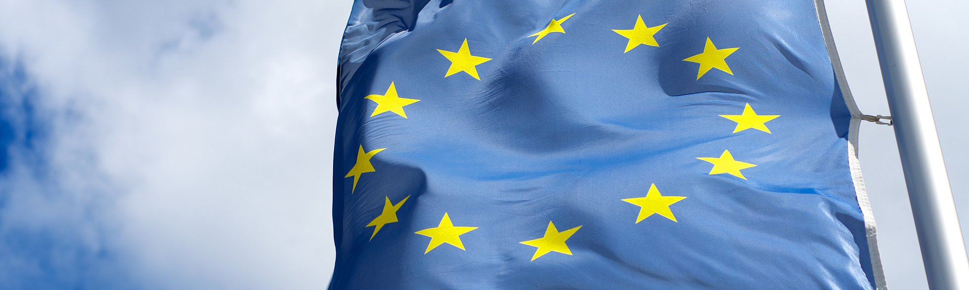 Flagge der Europäische Union weht auf einem Fahnenmast im Wind.