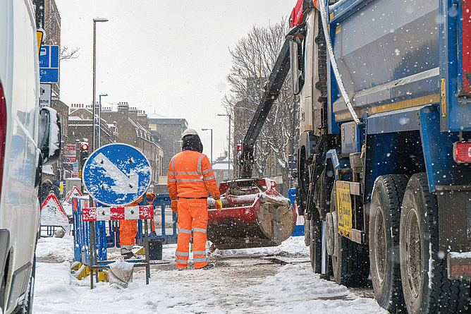 Baustelle auf einer Verkehrsstraße bei Schnee.