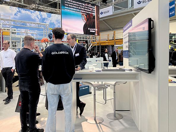 Beratung zu den Ausbildungs- und Einstiegsmöglichkeiten bei der BG BAU am bauma-Messestand Messebesucher am Stand der BG BAU.