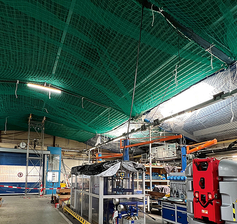 Arbeiten auf dem Dach: Personenauffangnetze inkl. Kleinteileschutznetz sind direkt unterhalb der Stahlkonstruktion mit Aufhängeseilenmontiert.
