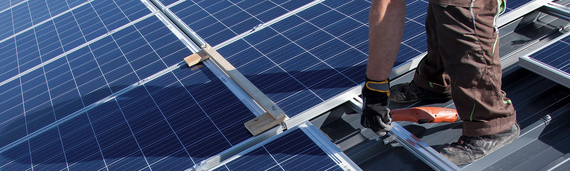Photovoltaikmodule werden von zwei Arbeitern auf einem Steildach installiert.