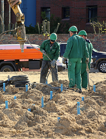 Drei Männer stehen während einer Kampfmittelsondierung auf aufgelockertem Boden.