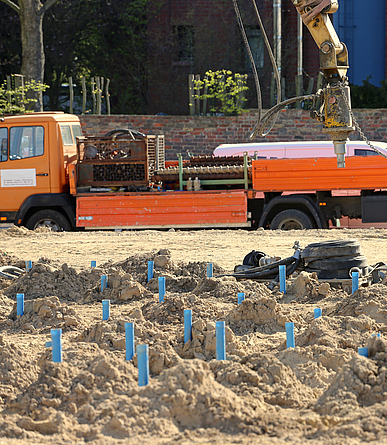 Drei Männer stehen während einer Kampfmittelsondierung auf aufgelockertem Boden.
