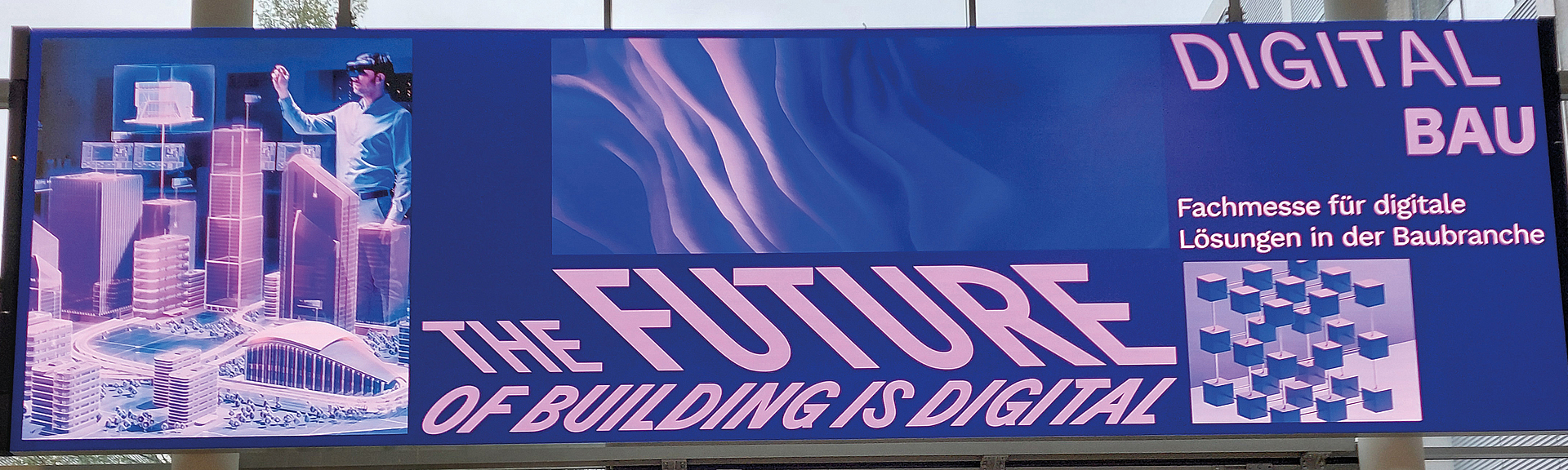 Banner über einem Eingang mit der Aufschrift „THE FUTURE OF BUILDING IS DIGITAL“ und „DIGITAL BAU – Fachmesse für digitale Lösungen in der Baubranche“.