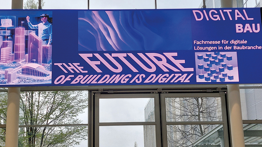 Banner über einem Eingang mit der Aufschrift „THE FUTURE OF BUILDING IS DIGITAL“ und „DIGITAL BAU – Fachmesse für digitale Lösungen in der Baubranche“.
