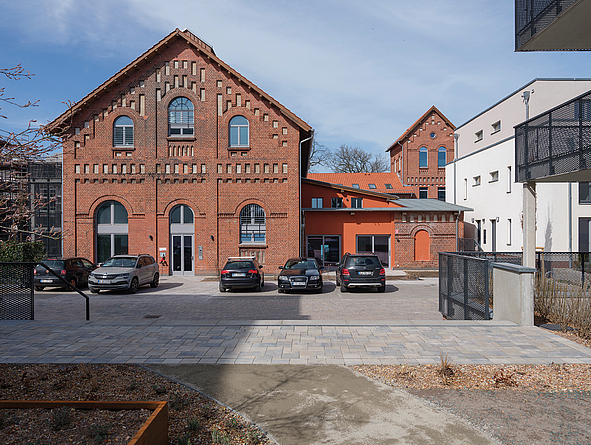 Saniertes Backsteingebäude mit symmetrischer Fassade und parkenden Autos davor.