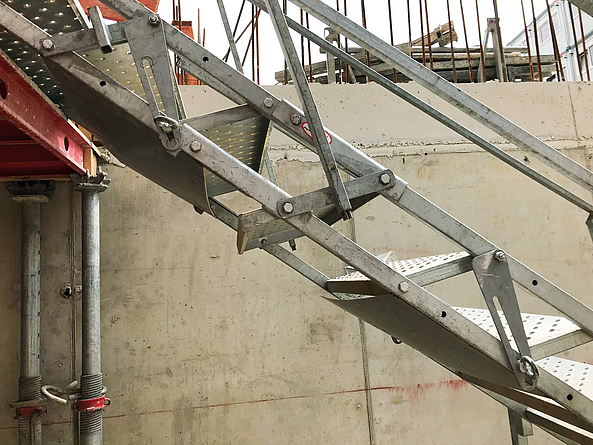 Treppe mit nivellierbaren Stufen im Montagezustand durch Anbauteile verlängerbar Oberer Teil einer Treppe, die in eine Baugrube führt. Die Stufen sind in der Höhe veränderbar.