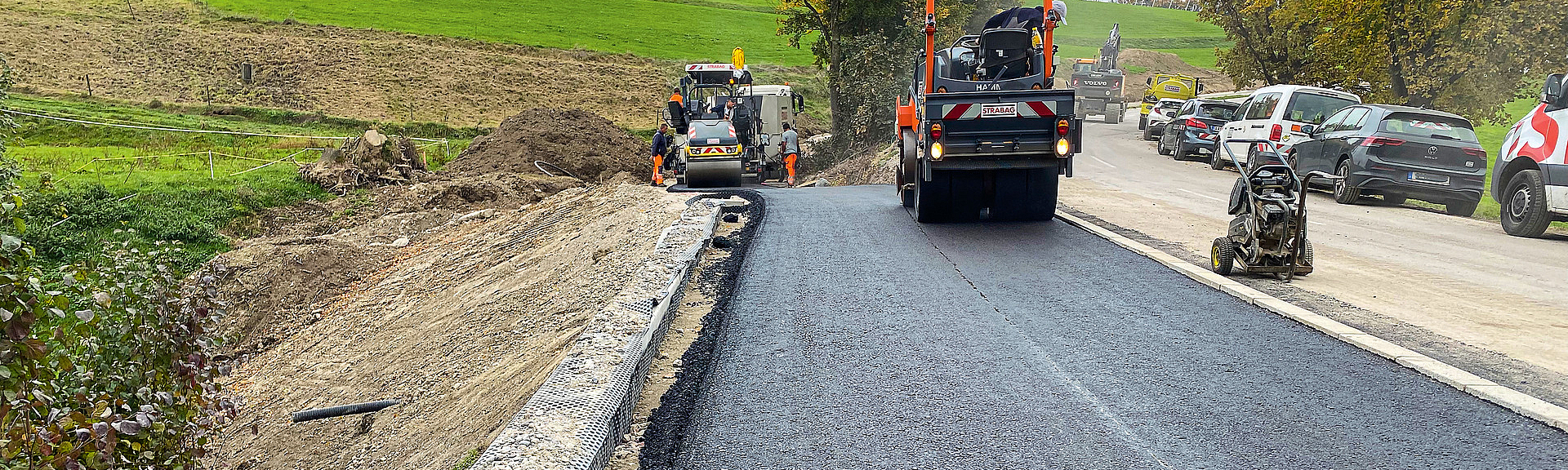 Eine Baumaschine fährt über eine frisch asphaltierte Straße.