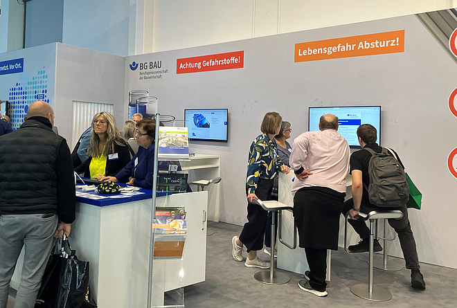 Kleine Personengruppen an verschiedenen Tischen an einem Messestand.