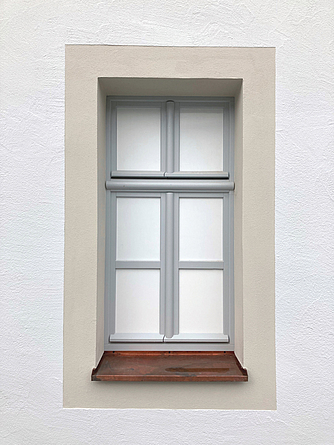 Geschlossenes Fenster mit einem neuen Farbrahmen und neuem Putz.