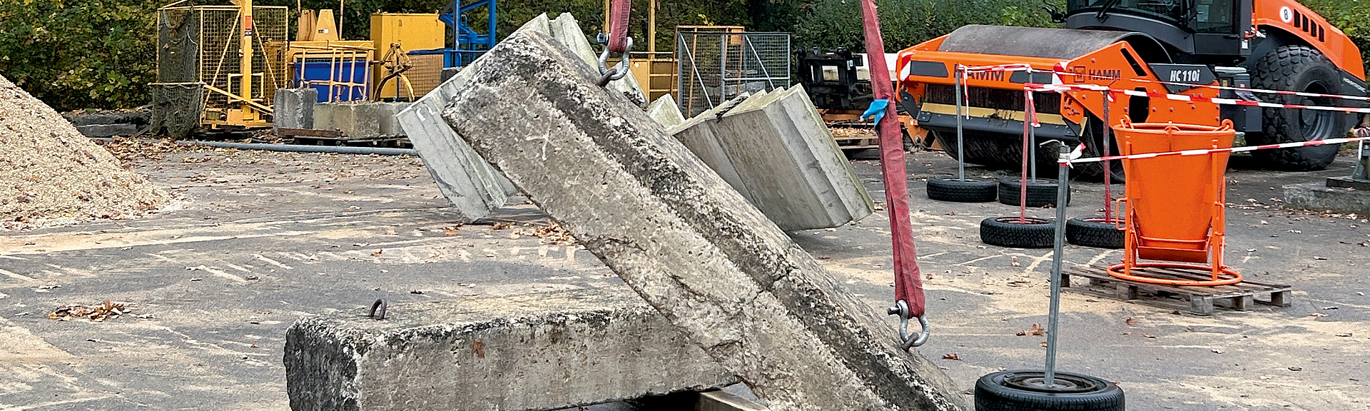 Kastenförmiger Balancer, an dem ein Betonteil mit zwei Seilen hängt.