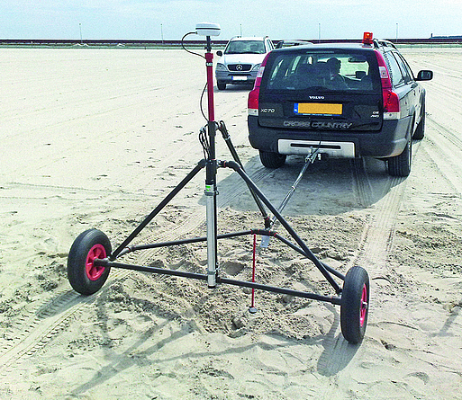 Zu sehen ist ein Van auf einer großen Sandfläche, der eine Magnetik-Sonde auf einer Zweirad-Konstruktion an einer Anhängerkupplung hinter sich herzieht.