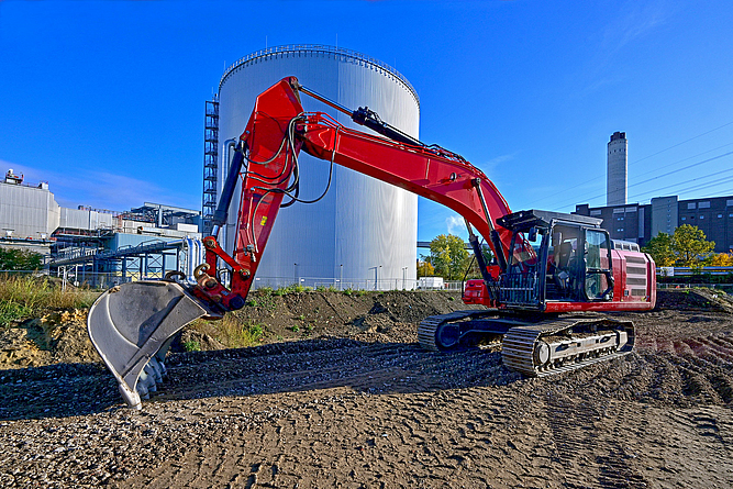 Bagger arbeitet im Baufeld vor dem Heißwasserspeicher im Kraftwerk Reuter-West.
